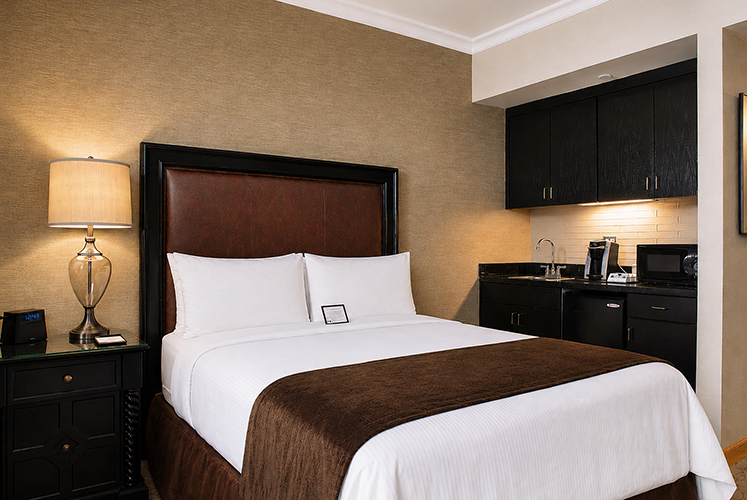 A queen-sized bed and a kitchenette in the Deluxe Queen with Kitchenette room.